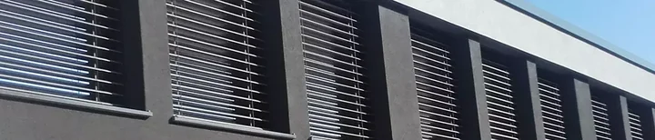 Dolga temna fasada z nizom oken in zunanjimi žaluzijami